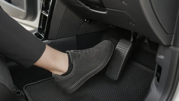 Foto kaki pengemudi di atas pedal gas pada mobil modern
